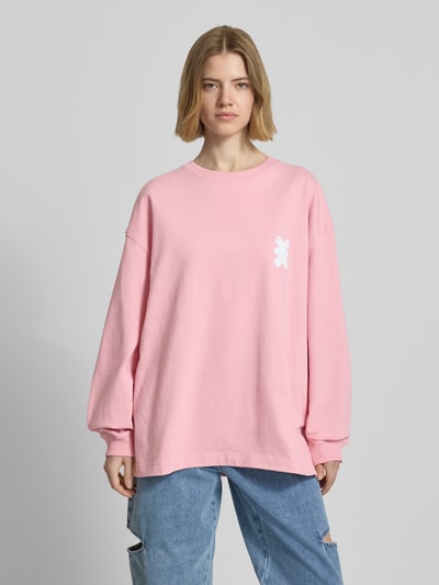 Frauenmodel trägt Sweatshirt mit Logo-Print von Karo Kauer in Rosa, lockerer Schnitt, reine Baumwolle, Rundhals, Ganzkörperansicht von vorne.