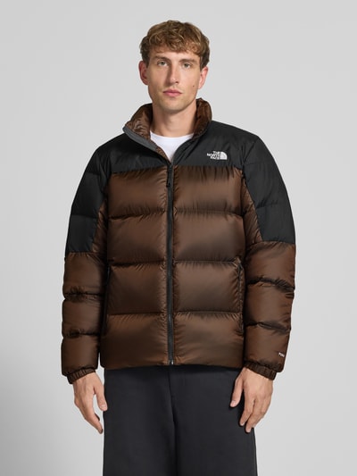 Männermodel trägt Regular Fit Jacke mit Daunen-Feder-Füllung Modell 'Diabolo' von The North Face in Braun und Schwarz, Stepp-Optik, Logo-Stitching, Stehkragen, Ganzkörperansicht von vorne. Rückenlänge 70 cm, Schulterbreite 47 cm, Brustweite 58 cm, Ärmellänge 69 cm.