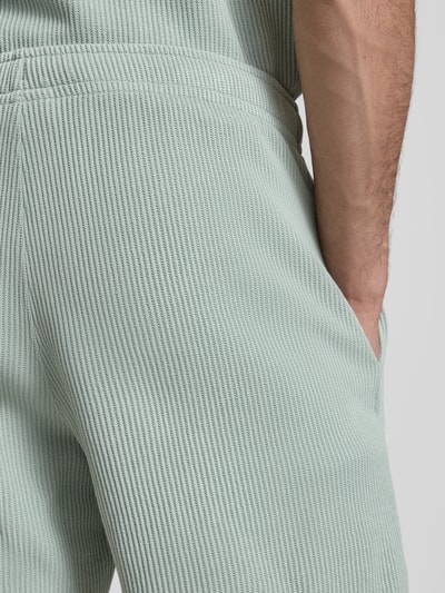 Männermodel trägt Shorts mit Strukturmuster und elastischem Bund von CHAMPION, Baumwoll-Mix, Struktur, Nahaufnahme Hüfte.