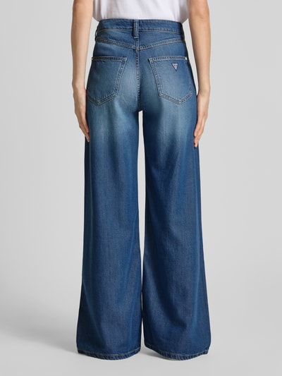 Frauenmodel trägt Wide Leg Jeans im 5-Pocket-Design Modell 'BELLFLOWER' von Guess, blauer Lyocell-Mix, ausgestellter Schnitt, Baumwoll-Anteil, Ganzkörperansicht Rückansicht