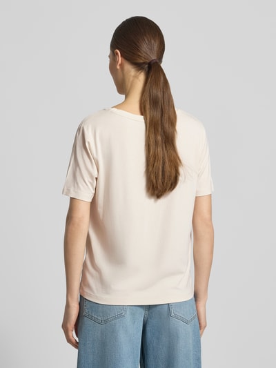 Männermodel trägt T-Shirt aus Viskose-Mix mit Brusttasche von monari w kolorze jasnym, krój loose fit, okrągły dekolt, brustasza, obszycie z kamieni stras, detal z logo, długość tyłu w rozmiarze 36: 56 cm, mieszanka wiskozy z dodatkiem streczu, Ganzkörperansicht Rückansicht.