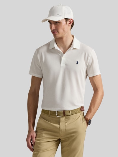 Männermodel trägt Regular Fit Poloshirt aus Baumwoll-Mix Modell 'TOUR PIQUE' von Polo Ralph Lauren, Optik: Unifarben, Logo-Detail, Polokragen, V-Ausschnitt, Verschluss: kurze Knopfleiste, Ärmelform: Kurzarm, Rumpfabschluss: mit Seitenschlitzen, Materialverarbeitung: Piqué, Farbe creme, glatte Textur, beige Hose, Ganzkörperansicht von vorne.