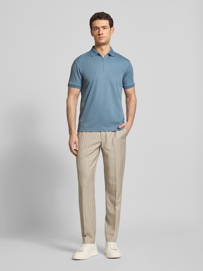 Männermodel trägt Regular Fit Poloshirt aus Bio-Baumwoll-Mix Modell 'FAVE' von SELECTED HOMME in Hellblau, Ganzkörperansicht von vorne. Unifarbenes Poloshirt mit Strick-Polokragen, kurzem Reißverschluss und kurzen Ärmeln mit Strick-Bündchen. Textur wirkt glatt und angenehm für den Alltag.