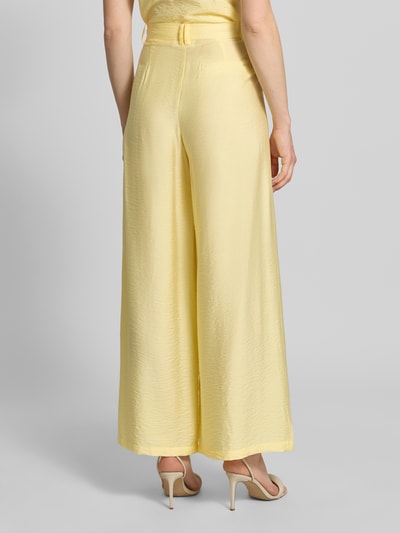Vrouwenmodel draagt Wide Leg Pants aus Viskose-Mix mit Eingrifftaschen van GUIDO MARIA KRETSCHMER WOMAN in lichtgeel met wijde pijpen, Franse steekzakken, knoop- en ritssluiting, uitlopende fit, model 'Finja', detailopname achteraan.