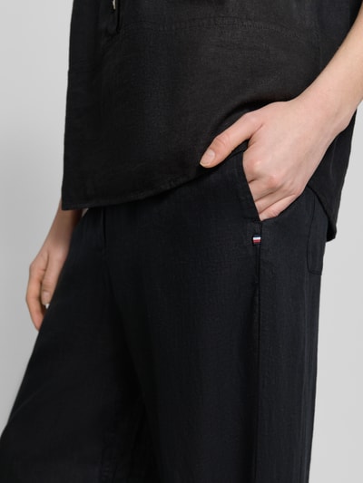 Frauenmodel trägt Loose Fit Weite Hose aus reinem Leinen von Tommy Hilfiger mit Allover-Muster in Schwarz, Nahaufnahme Hüfte.