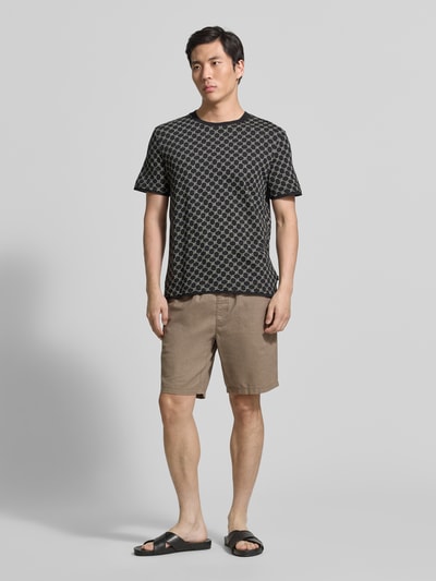 Männermodel trägt T-Shirt mit Logo-Muster und Rundhalsausschnitt von JOOP! Collection aus Baumwoll-Lyocell-Mix, Regular-Fit, neutrale Farben, weiche Textur, Rückenlänge bei Größe M 69 cm, Ganzkörperansicht von vorne.
