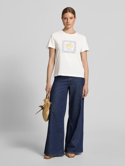 Frauenmodel trägt Regular Fit T-Shirt aus reiner Baumwolle von Tom Tailor, unifarben mit Motiv-Print, kombiniert mit Jeans, Ganzkörperansicht von vorne.