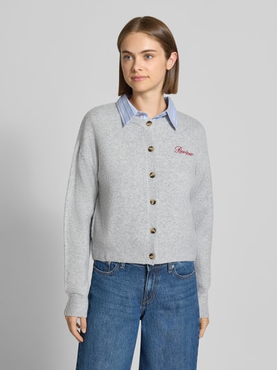 Modelka prezentuje kardigan rozpinany z wyhaftowanym logo Strickjacke mit Label-Stitching od REVIEW, szary, prążkowana faktura, elastyczna mieszanka materiałów, luźny krój, listwa guzikowa, prążkowane wykończenia, opuszczone ramiona, Długość tyłu w rozmiarze S: 54 cm, Długość rękawów w rozmiarze S: 58 cm, widok całej sylwetki z przodu.