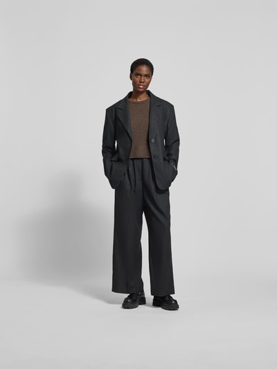 Frauenmodel trägt Stoffhose mit Bundfalten von black palms, Material-Mix mit Viskose-Anteil, lockerer Schnitt, Ganzkörperansicht von vorne.