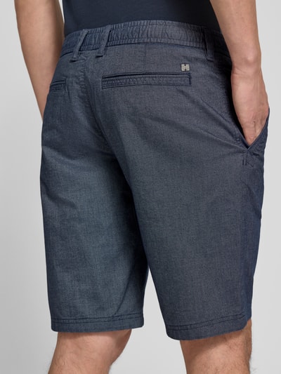 Mężczyzna nosi Regular Fit Chinoshorts aus Baumwoll-Mix Modell 'PHOENIX' von s.Oliver RED LABEL, bi-color, 5 kieszeni, elastyczny pas, zdjęcie całej sylwetki z tyłu.