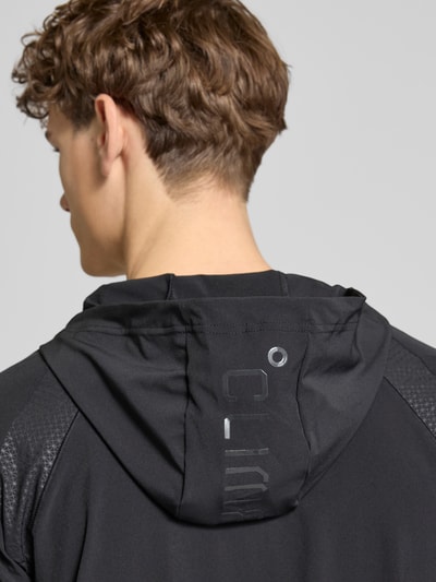 Männermodel trägt Sweatjacke mit Stretch-Anteil Modell 'TECH' von adidas Training in Schwarz mit Kapuze, Detailaufnahme Rückenansicht.