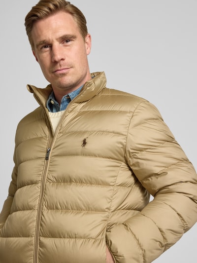 Männermodel trägt Regular Fit Steppjacke mit Logo-Stitching von Polo Ralph Lauren in Beige, Stehkragen, Reißverschluss, Nahaufnahme Oberkörper.