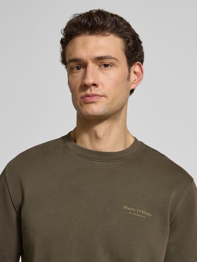 Männermodel trägt Regular Fit Sweatjacke aus reiner Baumwolle von Marc O'Polo in Oliv, unifarben, Label Print, Nahaufnahme Oberkörper.