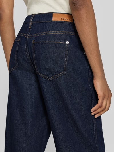 Frauenmodel trägt Straight Fit Jeans mit Knopfverschluss von COMMA aus Baumwoll-Lyocell-Mix in Dunkelblau, sichtbare Gesäßtaschen, Ganzkörperansicht Rückansicht.