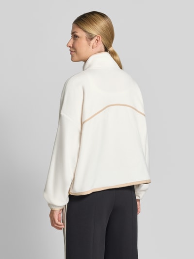 Vrouwenmodel draagt Relaxed Fit Pullover Troyer-Kragen Model 'Polar' van Fabletics, dames fleecejack in gebroken wit, schipperskraag, kangoeroezak, lange mouw, oversized schouder, fleece structuur, achterkantaanzicht.