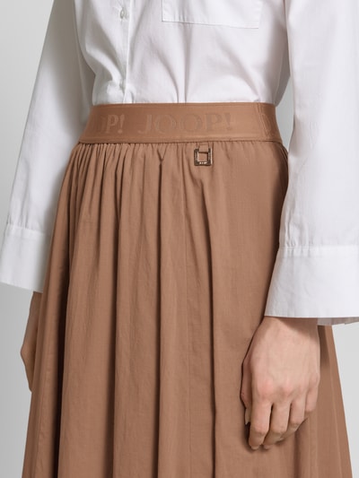 Frauenmodel trägt Midirock mit elastischem Logo-Bund von JOOP! aus reiner Baumwolle, A-Linie, Label-Detail, Nahaufnahme Oberkörper.