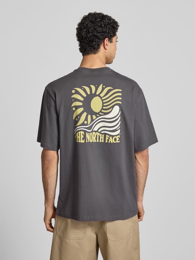 Männermodel trägt Oversized T-Shirt mit Logo-Print von The North Face in Grau aus Reine Baumwolle, Oversized-Fit, Rückenlänge 72 cm, Ganzkörperansicht Rückansicht.