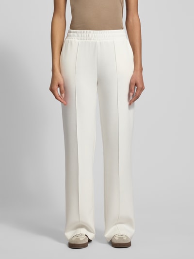 Kobiecy model nosi Sweatpants mit elastischem Bund od Christian Berg Woman, jasny kolor, luźny krój, francuskie kieszenie, widok z przodu.