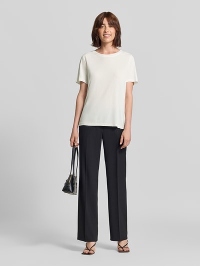 Frauenmodel trägt T-Shirt mit Rundhalsausschnitt von Fynch-Hatton in Weiß, Relaxed Fit, 1/2-Arm, kombiniert mit schwarzer Hose, Ganzkörperansicht von vorne. Rückenlänge bei Größe S: 62 cm.