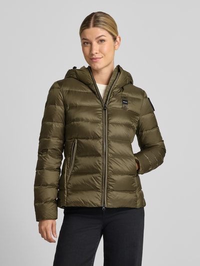 Modelka prezentuje kurtkę puchową z efektem pikowania model 'Charme' od Blauer USA, detal z logo, kaptur, zamek błyskawiczny dwustronny, krój taliowany, długość tyłu w rozmiarze S: 62 cm, szerokość ramion w rozmiarze S: 44 cm, szerokość w rozmiarze S: 43 cm, długość rękawów w rozmiarze S: 62 cm, zielony kolor, gładka faktura, widok całej sylwetki z przodu.