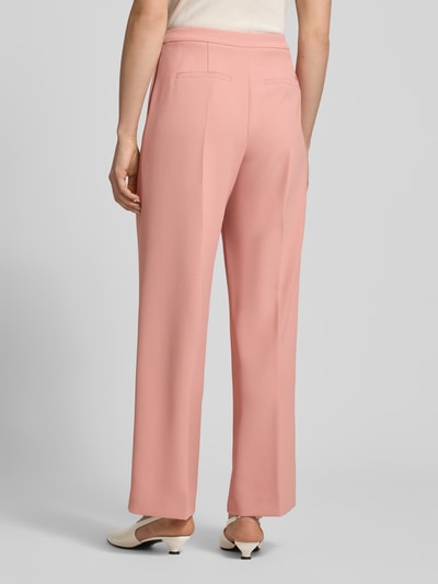 Frauenmodel trägt Hose mit Gesäßtaschen Modell 'Leya Miley' von MOS MOSH in Rosa mit weitem Bein, Bügelfalten, Ganzkörperansicht Rückansicht.