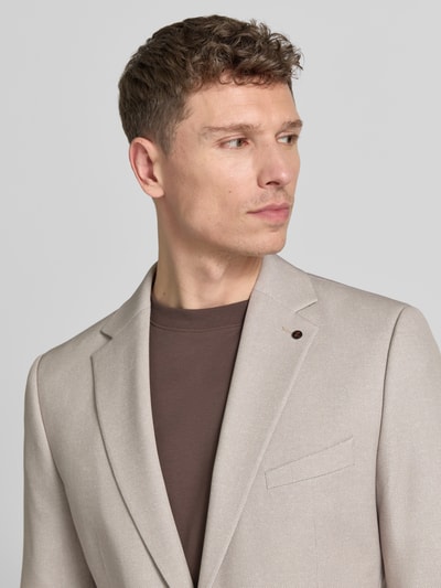 Männermodel trägt Sakko mit Pattentaschen Modell 'NICK' van Zuitable, materiaalmix met viscose, recht model, reverskraag, knoopsluiting, borstzak met pochet, beige kleur, fijne structuur, nahaufnahme bovenlichaam.