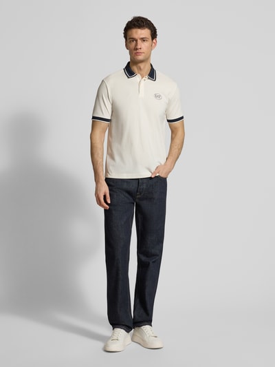 Männermodel trägt Regular Fit Poloshirt mit Logo-Print von EA7 Emporio Armani aus elastischem Baumwoll-Mix in Weiß, Polokragen, Kurzärmelig, Rückenlänge bei Größe M: 68 cm, Ganzkörperansicht von vorne.