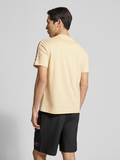 Männermodel trägt Regular Fit T-Shirt mit Logo-Patch von EA7 Emporio Armani in Beige, reine Baumwolle, Rückansicht, Ganzkörperansicht.