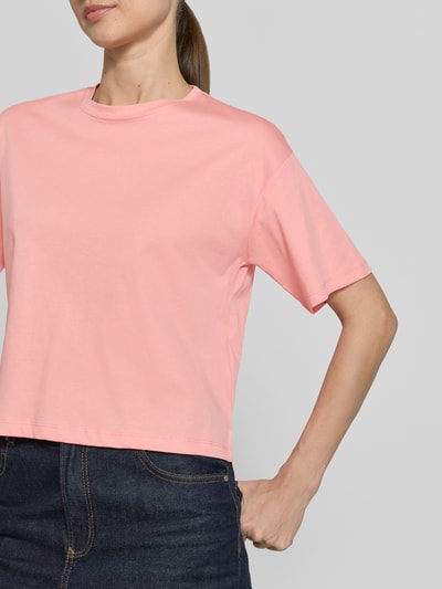 Vrouwenmodel draagt T-shirt met ronde hals model 'Moa Melea' van MSCH Copenhagen uit puur katoen, recht model, ruglengte maat XS/S 50 cm, lichtroze kleur, eenvoudige textuur, Nahaufnahme bovenlichaam.