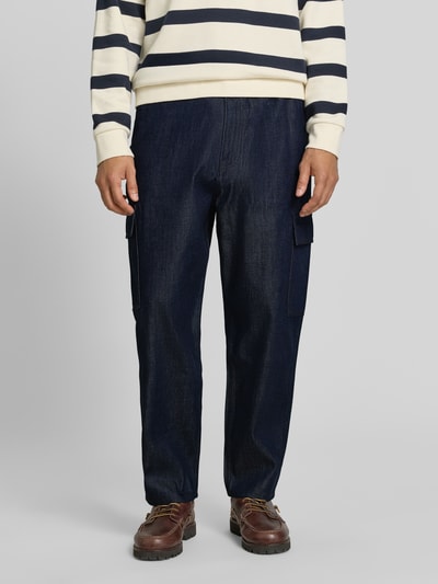 Männermodel trägt dunkelblaue Tapered Fit Jeans aus Baumwoll-Lyocell-Mix Modell 'Isak' von Marc O'Polo DENIM, Ganzkörperansicht von vorne.