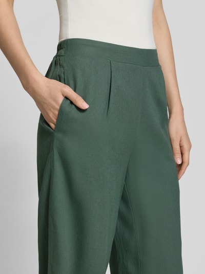 Kobiece model prezentuje Regular Fit Culotte aus Viskose-Leinen-Mix Modell 'MYMILO' von Vero Moda, efekt: jednolity kolor, krój regular fit, częściowo elastyczny ściągacz, wpuszczane kieszenie, wykończenie materiału: cieniowana przędza, mieszanka wiskozy i lnu, detal: szmaragdowa zieleń, półzbliżenie przód.