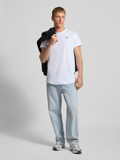 Männermodel trägt T-Shirt mit Label-Detail von G-Star RAW aus reiner Bio-Baumwolle, gerader Schnitt, Rundhalsausschnitt, fixierte Ärmelumschläge, Rückenlänge 76 cm bei Größe L, Ganzkörperansicht von vorne.