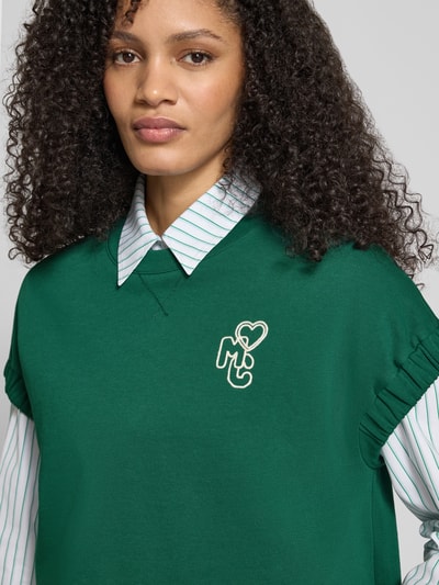 Frauenmodel trägt Relaxed Fit T-Shirt mit Logo-Detail von Marc Cain, Baumwoll-Mix, Rundhalsausschnitt, grün, Nahaufnahme Oberkörper.