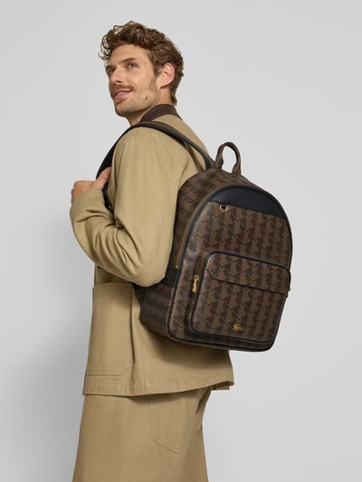 Męski model nosi plecak z wytłoczonym logo od Lacoste, brązowe wzory geometryczne, tekstura skóry, widok z tyłu, plecak Herren Rucksack von Lacoste