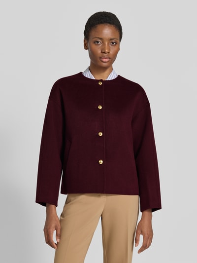 Frauenmodel trägt Relaxed Fit Kurzmantel aus Woll-Mix mit Kaschmir-Anteil von GANT, bordeaux, unifarben, goldene Knöpfe, seitliche Taschen, Rundhals, langarm, Ganzkörperansicht von vorne.