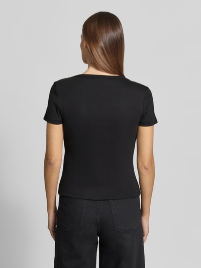 Frauenmodel trägt Slim Fit T-Shirt aus reiner Baumwolle von Tommy Hilfiger in Schwarz, unifarben, mit Logo-Detail und Zierknöpfen, Ganzkörperansicht Rückansicht.