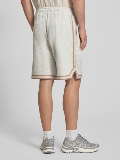 Männermodel trägt Shorts mit Strukturmuster und Label-Stitching von PEGADOR in Beige mit Eingrifftaschen, Reine Baumwolle, Regular-Fit, Ganzkörperansicht Rückansicht.