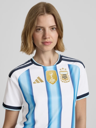 Frauenmodel trägt Regular Fit Trikot mit AFA-Applikation von adidas Sportswear, Mehrfarbig, Kontraststreifen, Logo-Stitching, Rundhals, Kurzarm, Nahaufnahme Oberkörper.