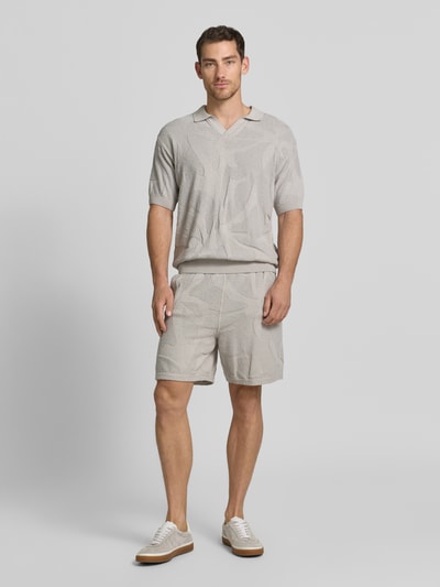 Männermodel trägt Relaxed Fit Poloshirt aus reiner Baumwolle Modell 'ASURFO' von BOSS Orange, Optik: Unifarben, Struktur, Ganzkörperansicht von vorne.