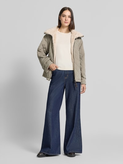 Frauenmodel trägt Steppjacke mit herausnehmbarer Kapuze Modell 'HENRIKE' von Blonde No. 8 in Beige, Kunstfell-Innenfutter, Ganzkörperansicht von vorne.