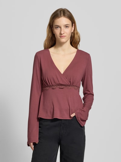Vrouwenmodel draagt Slim Fit langarmshirt uit viscosemix model 'SINI' van Only in wikkel-look met kanten details, diepe V-hals, labelstiksel, kleur oudroze, vooraanzicht van het bovenlichaam.