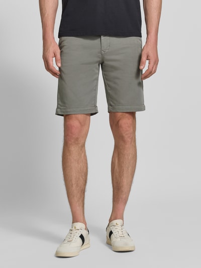 Männermodel trägt Bermudas mit Bindegürtel und französischen Eingrifftaschen von MAC aus Baumwoll-Mix mit Stretch-Anteil, Straight Fit, Knopf- und Reißverschluss, Gesäßleistentaschen, Label-Print auf der Rückseite, Farbe grau, glatte Textur, Ganzkörperansicht von vorne.