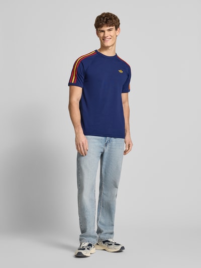 Męski model nosi T-Shirt mit Label-Stitching od adidas Originals, bawełna, krój regular fit, ściągacze, okrągły dekolt, długość tyłu 74 cm, widok całej sylwetki z przodu