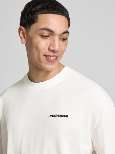 Männermodel trägt Oversized T-Shirt mit Logo-Stitching von Pegador, Reine Baumwolle, Oversized-Fit, Rundhalsausschnitt, Nahaufnahme Oberkörper.