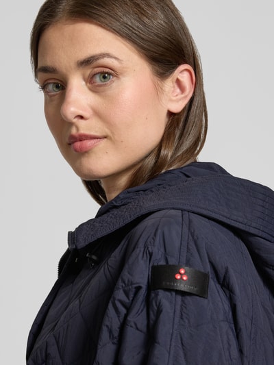 Frauenmodel trägt Relaxed Fit Jacke in Stepp-Optik Modell 'Texel' von Peuterey, dunkelblau, Stehkragen, Pattentaschen, Tunnelzug in der Taille, Nahaufnahme Oberkörper. Rückenlänge bei Größe 38: 80 cm, Schulterbreite: 50 cm, Brustweite: 72 cm, Ärmellänge: 59 cm.