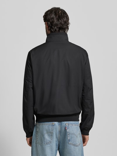 Männermodel trägt Regular Fit Jacke mit Stehkragen von MCNEAL in Schwarz, glatte Struktur, elastische Abschlüsse, Ganzkörperansicht Rückansicht, Herren Jacke, Reißverschluss, Eingrifftaschen, Rückenlänge 64 cm, Schulterbreite 43 cm, Brustweite 55 cm, Ärmellänge 67 cm.