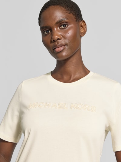 Vrouwenmodel draagt T-shirt met Label-Stitching van MICHAEL Michael Kors, puur katoen, recht model, ronde hals, ruglengte maat S 65 cm, close-up van het bovenlichaam.