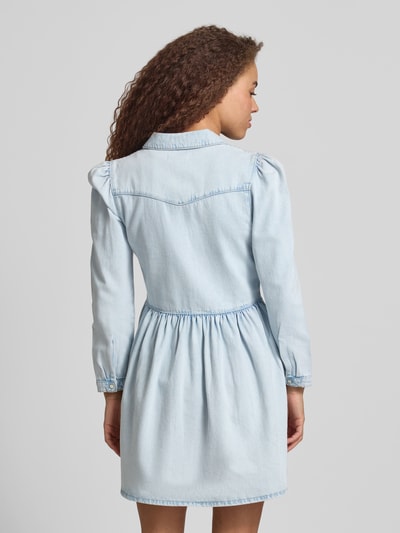 Frauenmodel trägt Mini-Jeanskleid aus reiner Baumwolle Modell 'CYRUS' von Only in heller Denim-Optik mit Knopfleiste, Ganzkörperansicht Rückansicht.