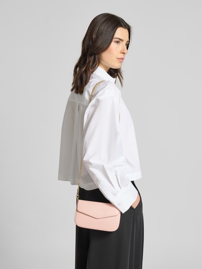 Kobiece model prezentuje Crossbody Bag mit Innenfach Modell 'VANJA' von Seidenfelt, różowy, efekt łańcuszka, zapięcie na magnes, przegródka wewnętrzna, szerokość w rozmiarze 1: 19 cm, długość w rozmiarze 1: 12 cm, głębokość w rozmiarze 1: 5 cm, długość paska na ramię w rozmiarze 1: 115 cm, zdjęcie całej sylwetki z przodu.