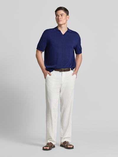 Männermodel trägt Relaxed Fit Poloshirt aus reiner Baumwolle Modell 'TORINO' von SELECTED HOMME in Dunkelblau, Ganzkörperansicht von vorne.